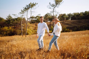 Young couple having fun walking and hugging n the park. Autumn weather. Relaxation, youth, love, lifestyle concept.