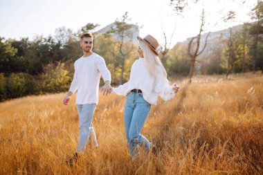 Young couple having fun walking and hugging n the park. Autumn weather. Relaxation, youth, love, lifestyle concept.