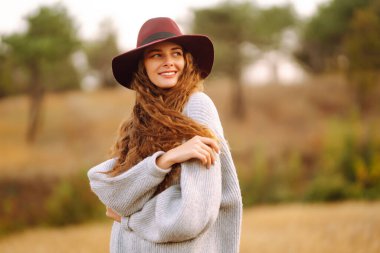 Stylish woman  in hat enjoying autumn weather in the park. Fashion, style concept.