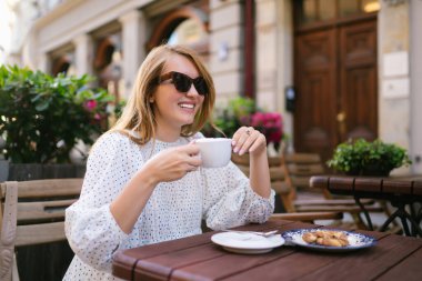 Happy woman in cafe on a city street. People, fashion, lifestyle, travel and vacations concept.