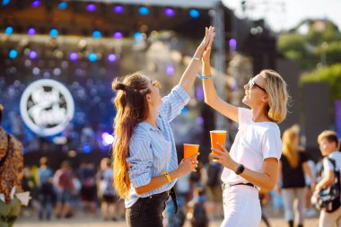 Two young woman  having a great time at a music festival. Happy girlfriends rinking beer and having fun at Beach party. Summer holiday, vacation concept.