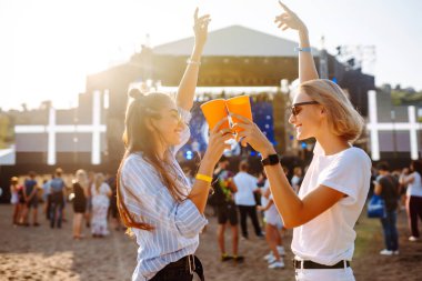 Two young woman  having a great time at a music festival. Happy girlfriends rinking beer and having fun at Beach party. Summer holiday, vacation concept.