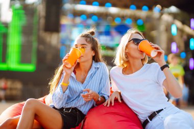 Two young woman  having a great time at a music festival. Happy girlfriends rinking beer and having fun at Beach party. Summer holiday, vacation concept.