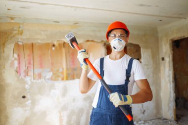 Young male builder in hard hat holding tools. Apartment repair and renovation concept.