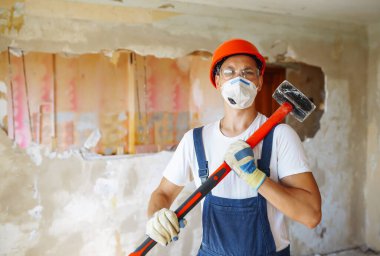 Young male builder in hard hat holding tools. Apartment repair and renovation concept.