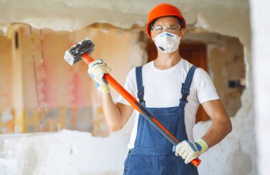 Young male builder in hard hat holding tools. Apartment repair and renovation concept.