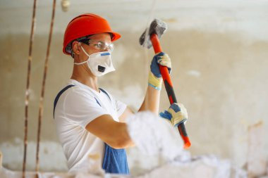 Young male builder in hard hat holding tools. Apartment repair and renovation concept.