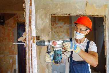 Young male builder in hard hat holding tools. Apartment repair and renovation concept.