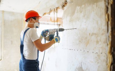 Young male builder in hard hat holding tools. Apartment repair and renovation concept.