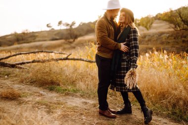 Stylish couple walking and hugging in the park. People, lifestyle, relaxation and vacations concept. Autumn Fashion, style concept.