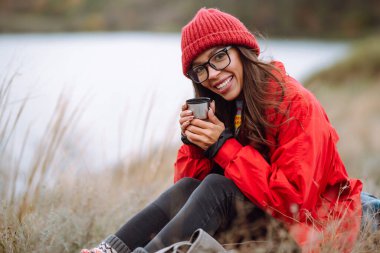 Soğuk bir sonbahar gününde termostan çay içen güzel bir kadın. Dinlenme, rahatlama, seyahat, yaşam tarzı konsepti.