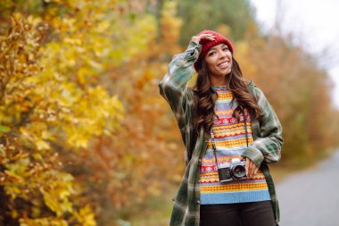 Genç ve güzel bir kadın retro kamerayla çekiliyor. Dinlenme, rahatlama, seyahat, yaşam tarzı konsepti.