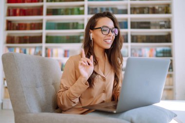 Kablosuz kulaklıklı genç bir kadın laptoptan arıyor. Çevrimiçi konferans, eğitim. Serbest Çalışan, İş, Eğitim Konsepti.