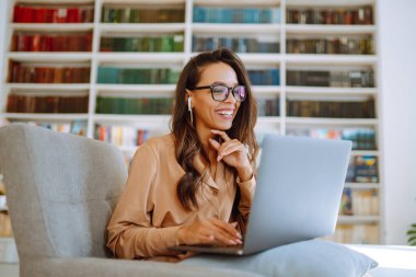 Kablosuz kulaklıklı genç bir kadın laptoptan arıyor. Çevrimiçi konferans, eğitim. Serbest Çalışan, İş, Eğitim Konsepti.