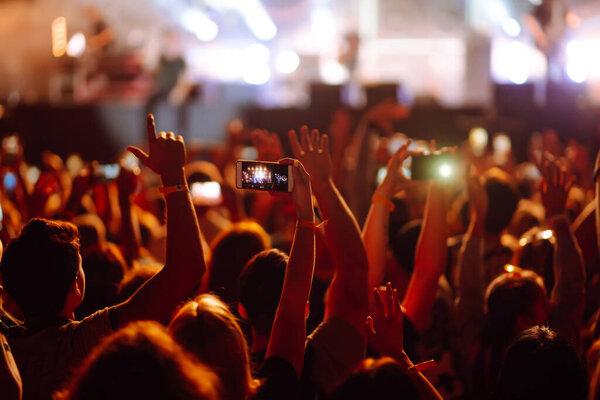 Using a smartphone in a public event, live music festival.  Summer holiday, vacation concept. 