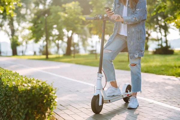 Açık havada elektrikli scooter kullanan kadın bacakları. Aktif hayat. Ekolojik ulaşım kavramı.