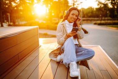 Dışarıda kulaklıkla müzik dinleyen genç bir kadın. İnsanların, müziğin, duyguların konsepti.