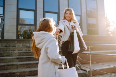 Alışveriş merkezinin yakınında torbaları olan şık bir anne ve küçük bir kız. Sonbahar alışverişi. Satın almalar, Kara Cuma, indirimler, satış konsepti.