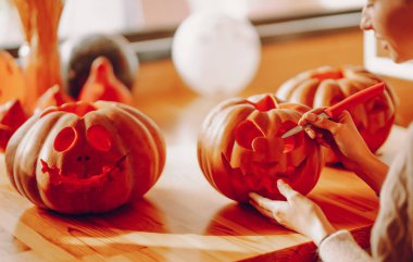 Cadılar bayramı için balkabağı oyan genç bir kadın. Cadılar Bayramı, dekorasyon ve tatil konsepti.