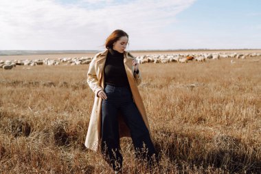 Sonbahar tarlasında poz veren şık elbiseli genç bir kadın. Doğa, moda, tatil ve yaşam tarzı. Seyahat ve macera.