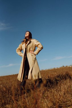 Sonbahar tarlasında poz veren şık elbiseli genç bir kadın. Doğa, moda, tatil ve yaşam tarzı. Seyahat ve macera.