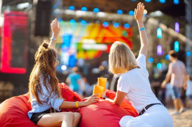 İki bayan arkadaş bira içer ve müzik festivalinde eğlenir. Yaz tatili, tatil konsepti.