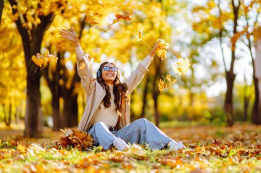 Genç kadın gülümsüyor ve akçaağaç yaprakları fırlatıyor..