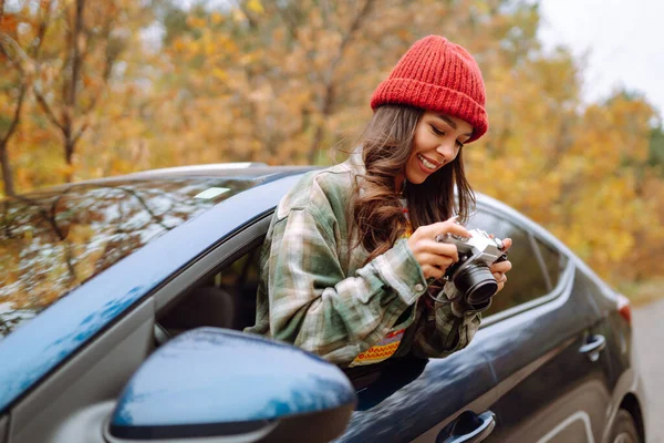 年轻女子从车窗用相机拍照 生活方式概念 — 图库照片