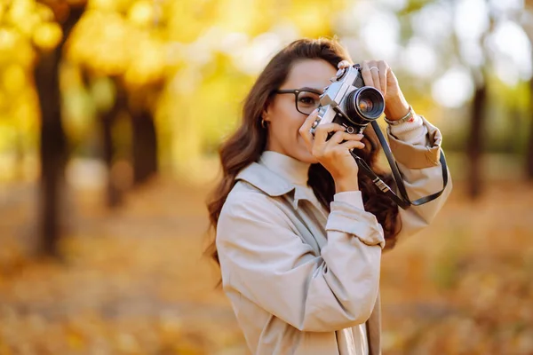 秋の森で写真を撮る若い女性 黄色の葉を持つ秋の公園を歩く女性 — ストック写真