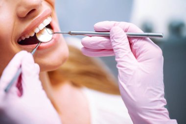 Diş tedavisi sırasında dişçi koltuğunda oturan genç bir kadın. Diş sağlığı önlemesine genel bakış. Sağlıklı Gülümse.