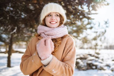 Güzel bir kadın karlı ağaçların arasında duruyor ve ilk karın tadını çıkarıyor. Mutlu kış zamanları.. 