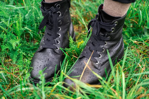 Молода жінка в чорних шкіряних мокрих чоботях у зеленій свіжій траві в парку — стокове фото
