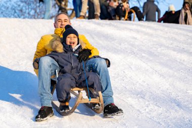 Babası ve küçük afro amerikalı ya da latin oğlu karlı dağdan aşağı kayıyor.