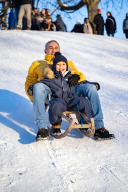 Babası ve küçük afro amerikalı ya da latin oğlu karlı dağdan aşağı kayıyor.