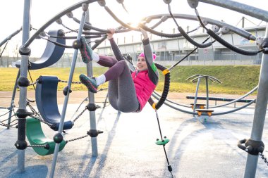 Spor barında elleri asılı, sıcacık formalı genç bir kadın.