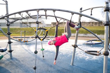 Spor barında bacaklarıyla sallanan sıcacık spor elbiseli genç bir kadın.