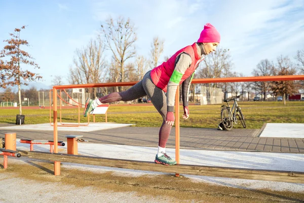 Mujer en forma joven en ropa de fitness colorida de pie en rack manteniendo el equilibrio — Foto de Stock