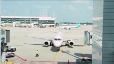 White airplane parking after landing to airport terminal docking bay on runway