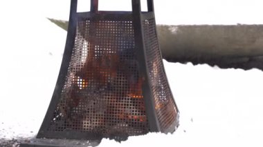 Metallic heater wooden campfire in snowy park on cloudy winter calm cozy day