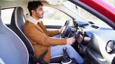 Young arabic eastern man in manual gear box car starts engine with ignition key