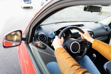 Man casually dressed with hands holding driving wheel riding car at daytime