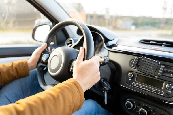 Man casually dressed with hands holding driving wheel riding car at daytime