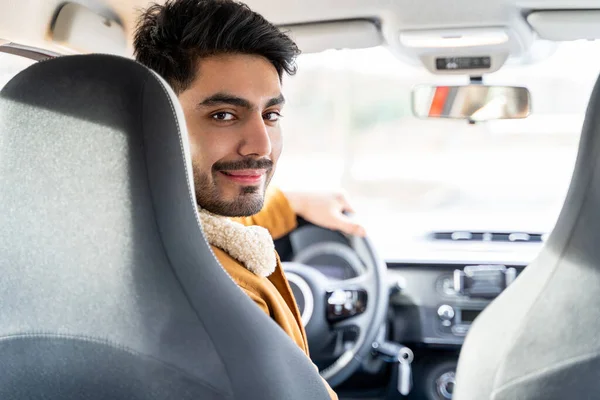 Man casually dressed with hand on driving wheel looking on backseat in camera Fotos De Stock Sin Royalties Gratis