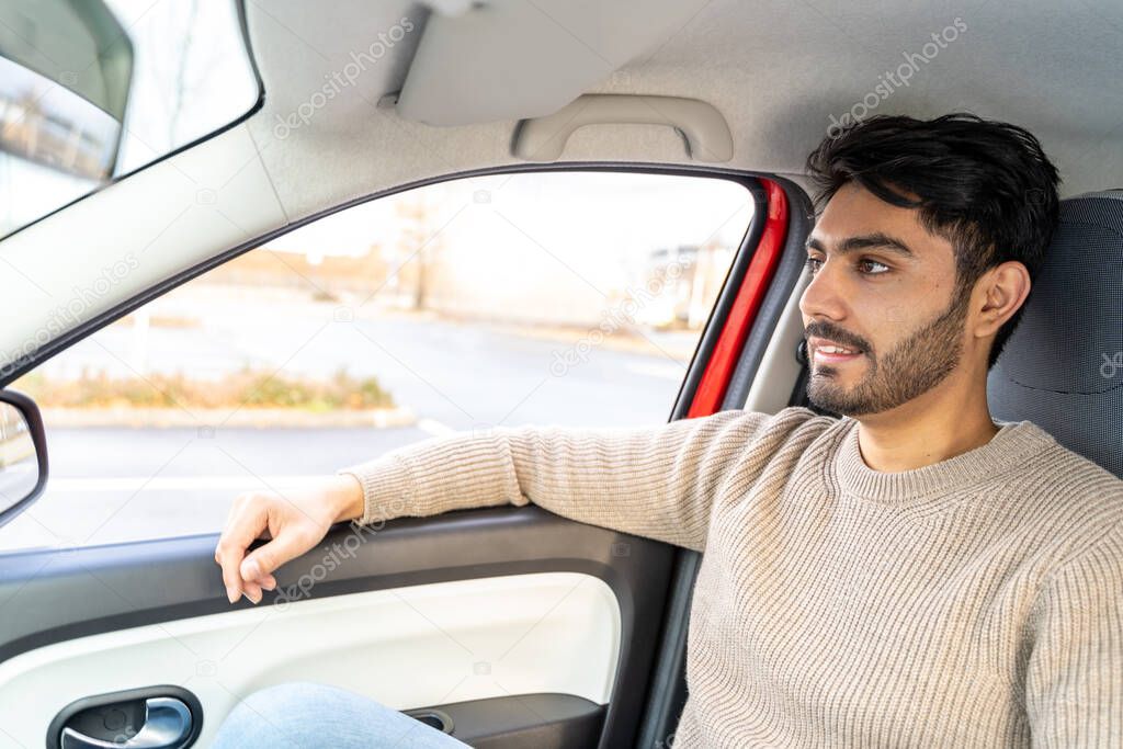 Man in sweater sitting on passengers seat having ride in car at daytime