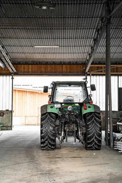 Zelený traktor s velkými koly v garáži u zemědělských přípravků ve dne — Stock fotografie