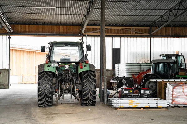 Zelený traktor s velkými koly v garáži u zemědělských přípravků ve dne — Stock fotografie
