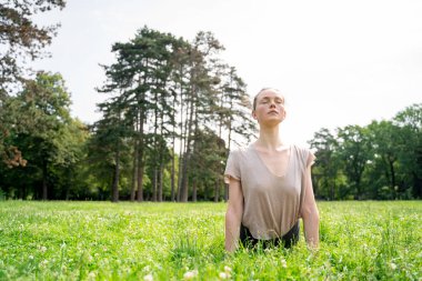 Hafif pamuklu tişört giyen, aerobik yapan, sırt esneten, güneş selamı veren, antrenmandan sonra köpek yogasına bakan ya da yaz parkında çimlerde pilates yapan beyaz bir kadın.