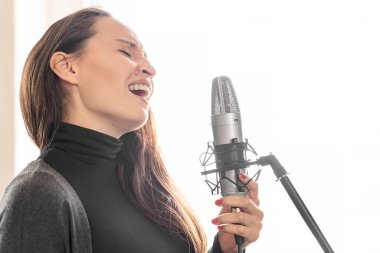Genç Japon ya da Avrupalı uzun saçlı esmer kadın Mike 'a güpegündüz müzik stüdyosunda ya da konser sahnesinde şarkı söylüyor. Sınavdan önce ya da dersten önce hazırlanma alıştırması yapıyorum.