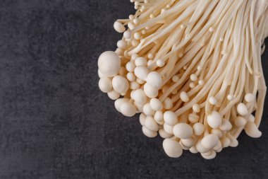 Taze Enoki mantarları seçilmiş odaklı olarak siyah zemin üzerinde bulunur. Enoki, ayrıca kadife şiş olarak da bilinir, Physalacriaceae familyasından yenilebilir bir mantar türüdür.. 