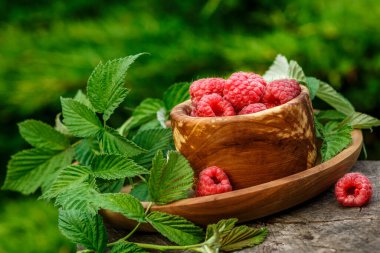 Tahta kasede taze sulu ahududu. Eski ahşap bir masanın üzerinde ahudududularla dolu bir yaz. Uzayı kopyala. Ahududu reçeli kavanozu ve ahşap arka planda taze böğürtlen.